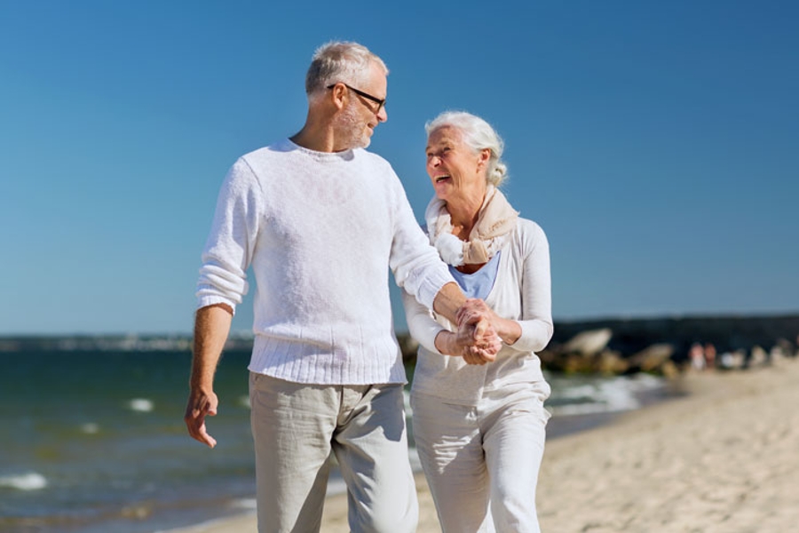 Ein Paar genießt die gemeinsame Rentenzeit bei einem Spaziergang am Ostseestrand.